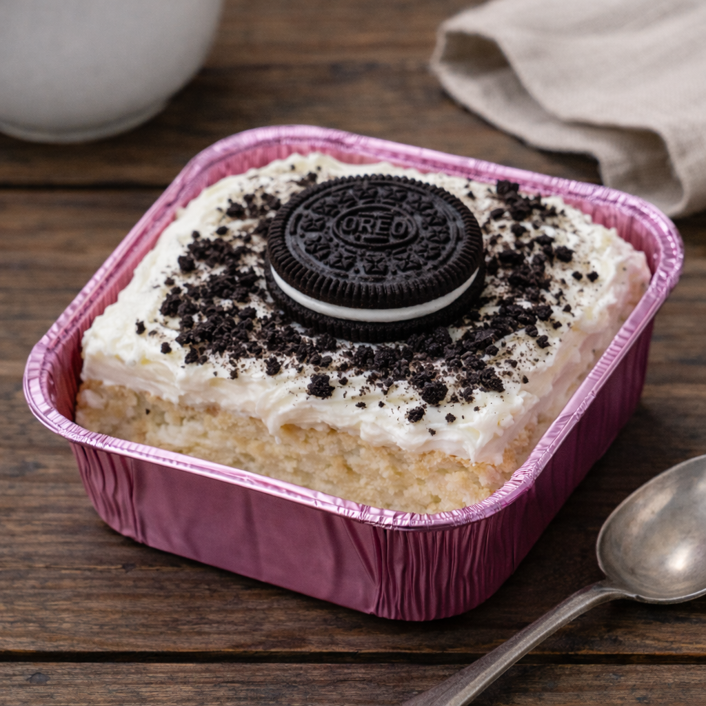 Individual Tres Leches Cake Dessert Small tres leches cake in foil container topped with whipped cream, cherry, sliced strawberry, and mint leaf